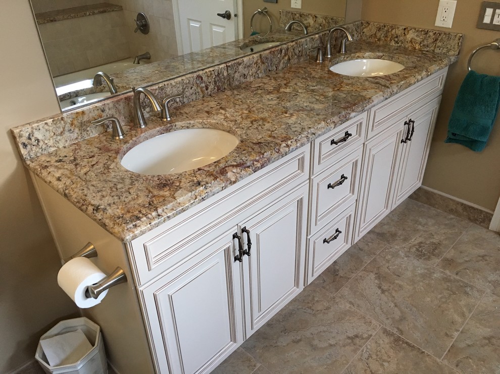 Exempel på ett mellanstort klassiskt en-suite badrum, med luckor med upphöjd panel, vita skåp, ett badkar i en alkov, en dusch i en alkov, en toalettstol med separat cisternkåpa, beige kakel, keramikplattor, beige väggar, travertin golv, ett undermonterad handfat och granitbänkskiva
