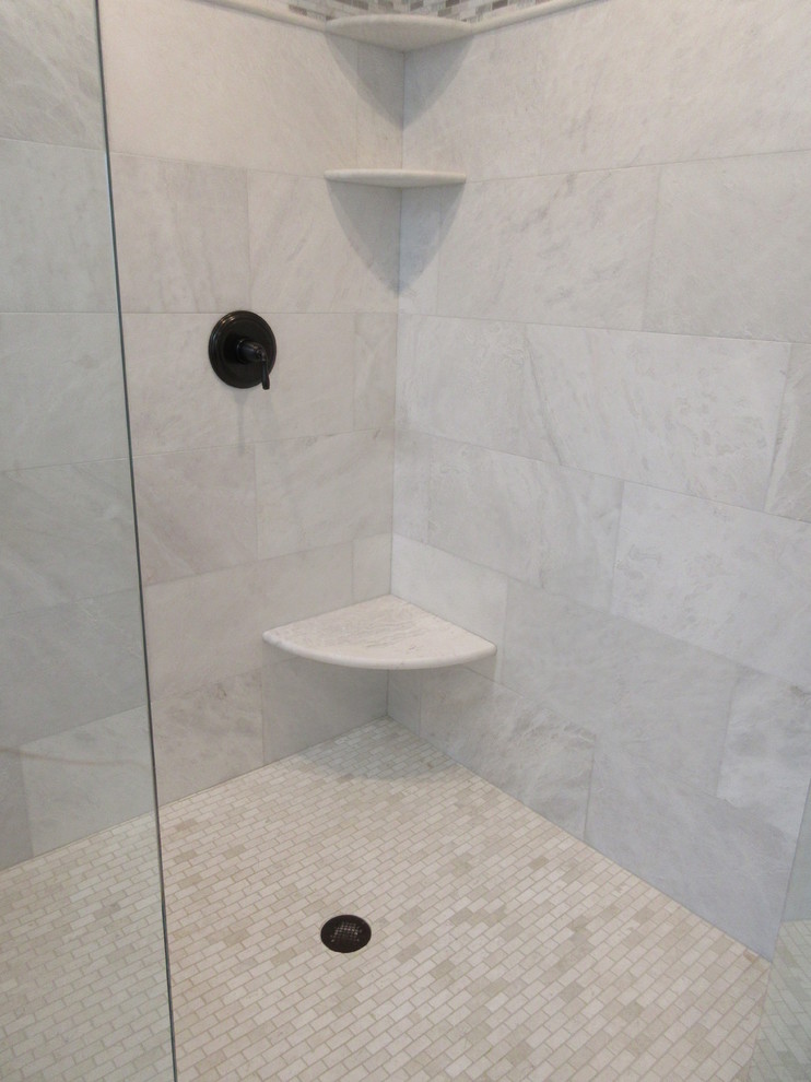 Bild på ett stort funkis vit vitt badrum, med möbel-liknande, bruna skåp, ett hörnbadkar, en hörndusch, en toalettstol med hel cisternkåpa, vit kakel, marmorkakel, grå väggar, marmorgolv, ett undermonterad handfat, granitbänkskiva, vitt golv och dusch med gångjärnsdörr