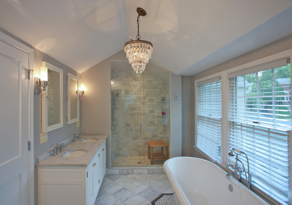 Inredning av ett klassiskt mellanstort en-suite badrum, med ett undermonterad handfat, luckor med infälld panel, vita skåp, ett fristående badkar, vit kakel, grå väggar och en dusch i en alkov