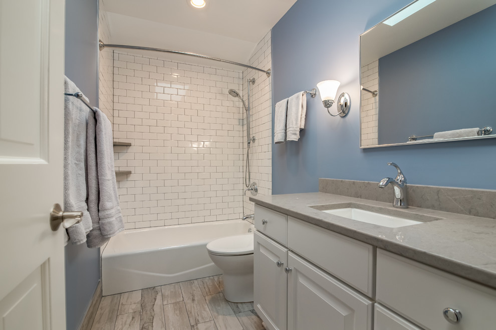 Idéer för ett mellanstort klassiskt en-suite badrum, med släta luckor, ett hörnbadkar, en dusch/badkar-kombination, en vägghängd toalettstol, vit kakel, glaskakel, blå väggar, linoleumgolv, ett nedsänkt handfat, bänkskiva i kvartsit och med dusch som är öppen
