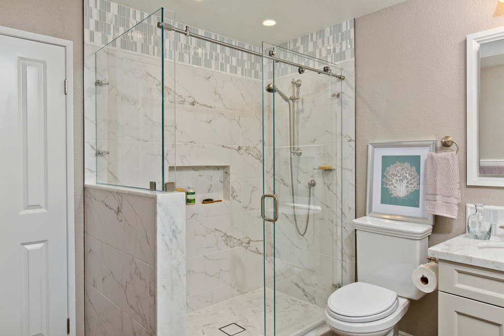 Klassisk inredning av ett stort en-suite badrum, med skåp i shakerstil, vita skåp, en hörndusch, en toalettstol med separat cisternkåpa, vit kakel, porslinskakel, grå väggar, klinkergolv i keramik, ett undermonterad handfat och marmorbänkskiva