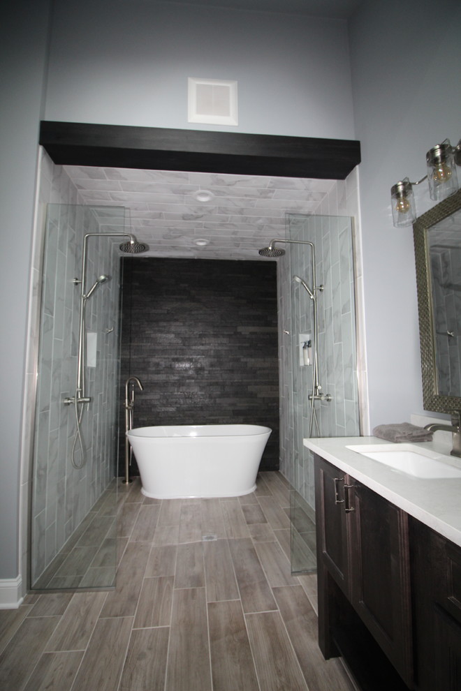 Aménagement d'une grande salle de bain principale classique en bois foncé avec une baignoire indépendante, une douche double, un carrelage beige, des carreaux de porcelaine, un mur gris, parquet clair, un lavabo encastré, un plan de toilette en granite, un sol marron et un plan de toilette gris.
