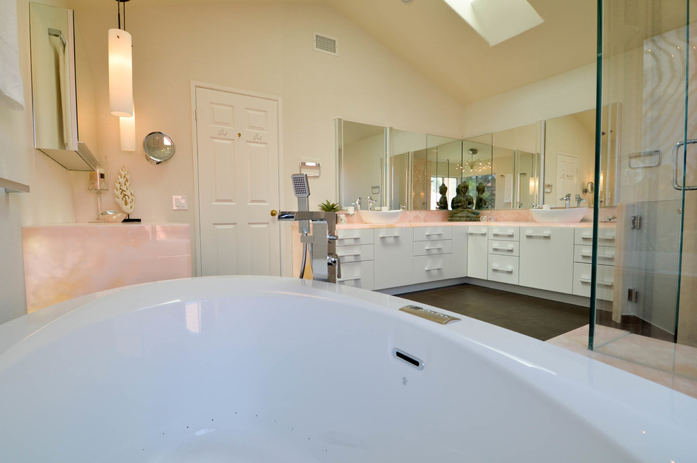 Exempel på ett stort modernt en-suite badrum, med ett fristående handfat, släta luckor, vita skåp, bänkskiva i onyx, ett fristående badkar, en kantlös dusch, en bidé, brun kakel, porslinskakel, vita väggar och klinkergolv i porslin
