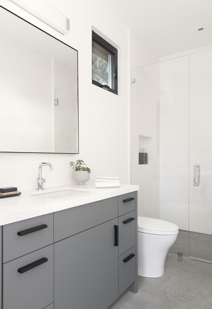 Exempel på ett modernt vit vitt badrum med dusch, med släta luckor, grå skåp, en kantlös dusch, vit kakel, keramikplattor, vita väggar, betonggolv, ett undermonterad handfat, bänkskiva i kvarts, grått golv och dusch med gångjärnsdörr