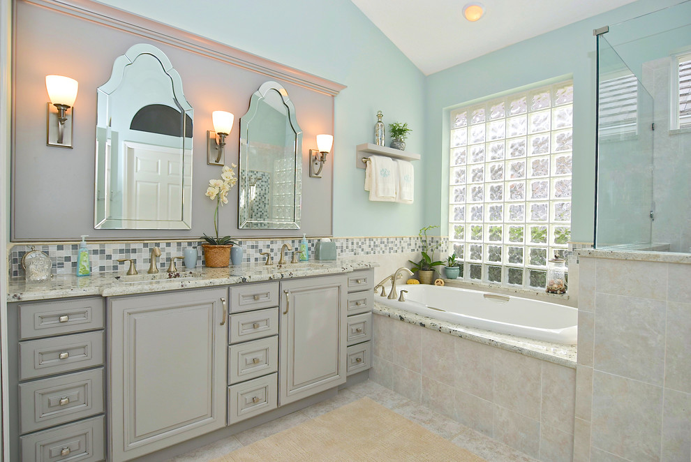 На фото: главная ванная комната среднего размера в классическом стиле с серыми фасадами, гидромассажной ванной, бежевой плиткой, керамогранитной плиткой, синими стенами, полом из керамогранита, врезной раковиной, столешницей из гранита, угловым душем, фасадами с выступающей филенкой, бежевым полом, душем с распашными дверями и серой столешницей