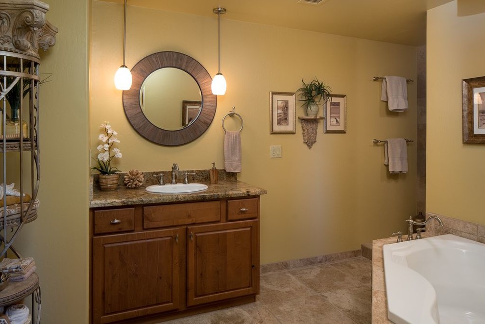 Aménagement d'une grande salle d'eau classique en bois brun avec un placard avec porte à panneau encastré, une baignoire posée, un mur beige, un sol en travertin, un lavabo posé et un plan de toilette en granite.