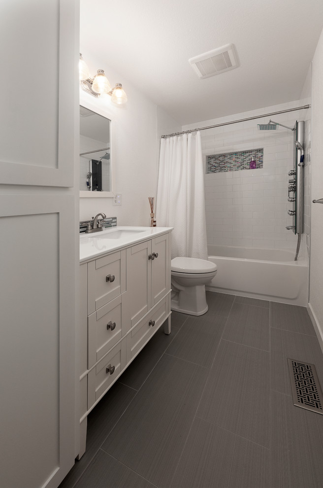 Cette image montre une salle de bain style shabby chic de taille moyenne avec une baignoire posée, un combiné douche/baignoire, un carrelage blanc, des carreaux de porcelaine, un mur blanc, un sol en carrelage de porcelaine, un sol gris, une cabine de douche avec un rideau, un placard à porte shaker, des portes de placard blanches, WC à poser, un plan de toilette en quartz, un plan de toilette turquoise et un lavabo intégré.
