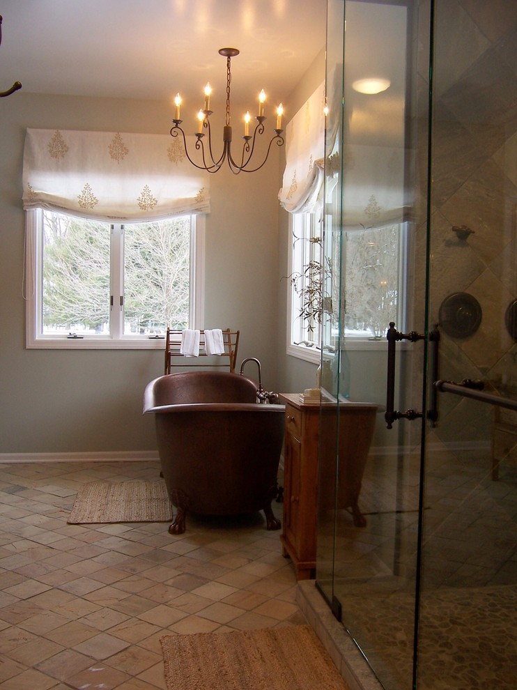 Modelo de cuarto de baño principal rústico de tamaño medio con armarios abiertos, puertas de armario de madera oscura, bañera con patas, ducha empotrada, paredes beige y encimera de madera