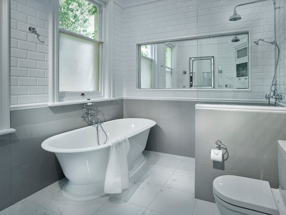 Inredning av ett modernt mellanstort en-suite badrum, med ett fristående badkar, en öppen dusch, en toalettstol med hel cisternkåpa, vita väggar, grå kakel och med dusch som är öppen