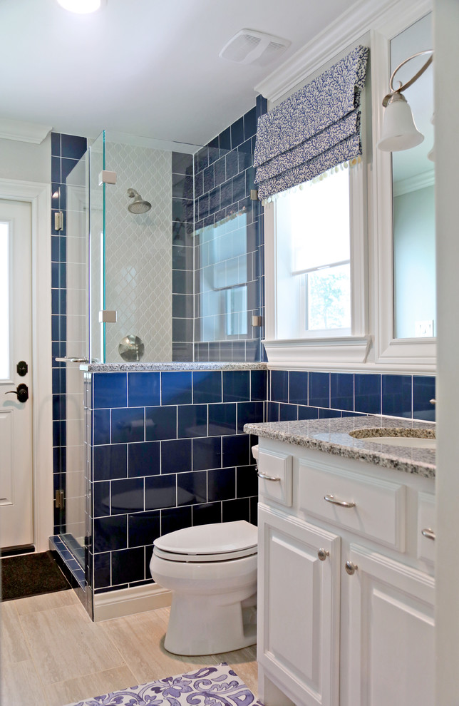 Photo of a small classic shower room bathroom in Other with raised-panel cabinets, white cabinets, an alcove shower, a one-piece toilet, blue tiles, ceramic tiles, blue walls, light hardwood flooring, a submerged sink, granite worktops, brown floors, a hinged door, white worktops, a single sink and a built in vanity unit.