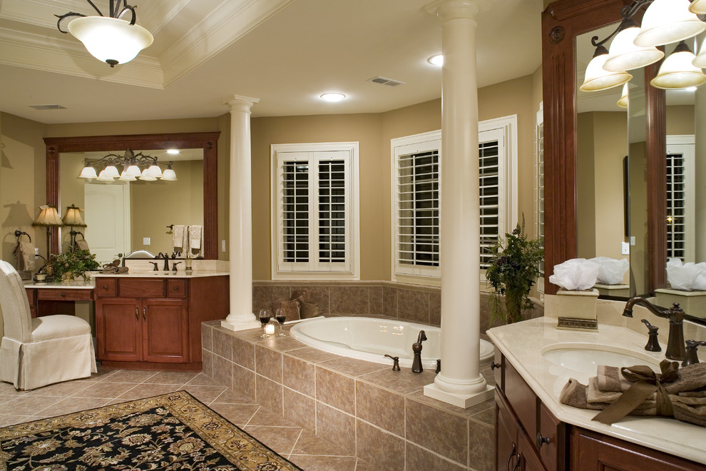 Example of a classic beige tile drop-in bathtub design in Chicago with an undermount sink, raised-panel cabinets and medium tone wood cabinets