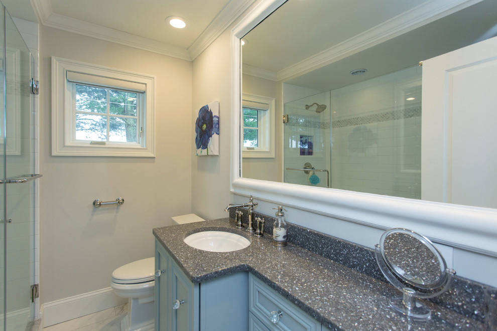 Example of a small transitional kids' white tile and ceramic tile ceramic tile and gray floor alcove shower design in Boston with recessed-panel cabinets, blue cabinets, a two-piece toilet, beige walls, an undermount sink, terrazzo countertops and a hinged shower door