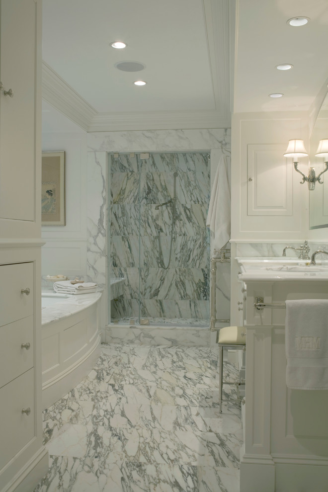 Photo of a large traditional ensuite bathroom in Boston with a submerged sink, beaded cabinets, white cabinets, marble worktops, a submerged bath, an alcove shower, a one-piece toilet, white tiles, stone tiles, white walls and marble flooring.
