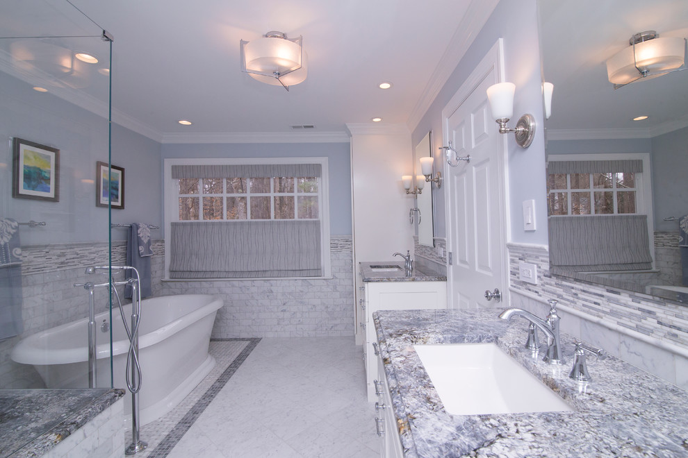 На фото: большая главная ванная комната в стиле неоклассика (современная классика) с фасадами в стиле шейкер, белыми фасадами, отдельно стоящей ванной, белой плиткой, мраморным полом, столешницей из гранита, двойным душем, раздельным унитазом, мраморной плиткой, синими стенами, врезной раковиной, белым полом, душем с распашными дверями и синей столешницей с