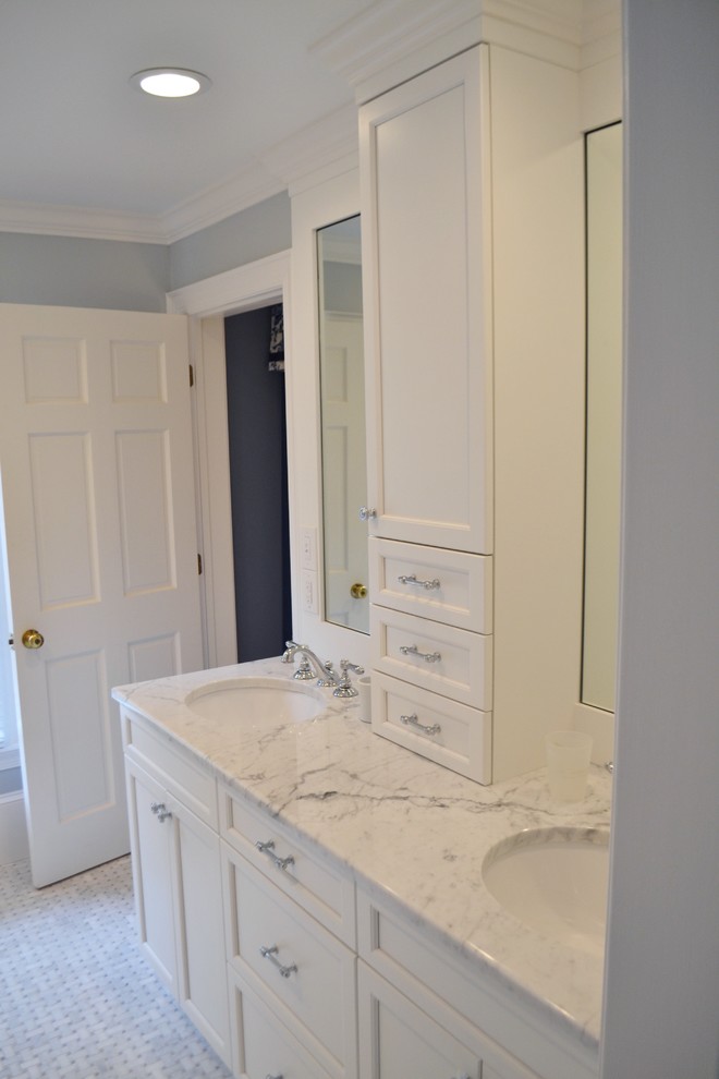 Cette image montre une salle de bain principale traditionnelle avec un lavabo encastré, des portes de placard blanches, un plan de toilette en marbre et un mur gris.