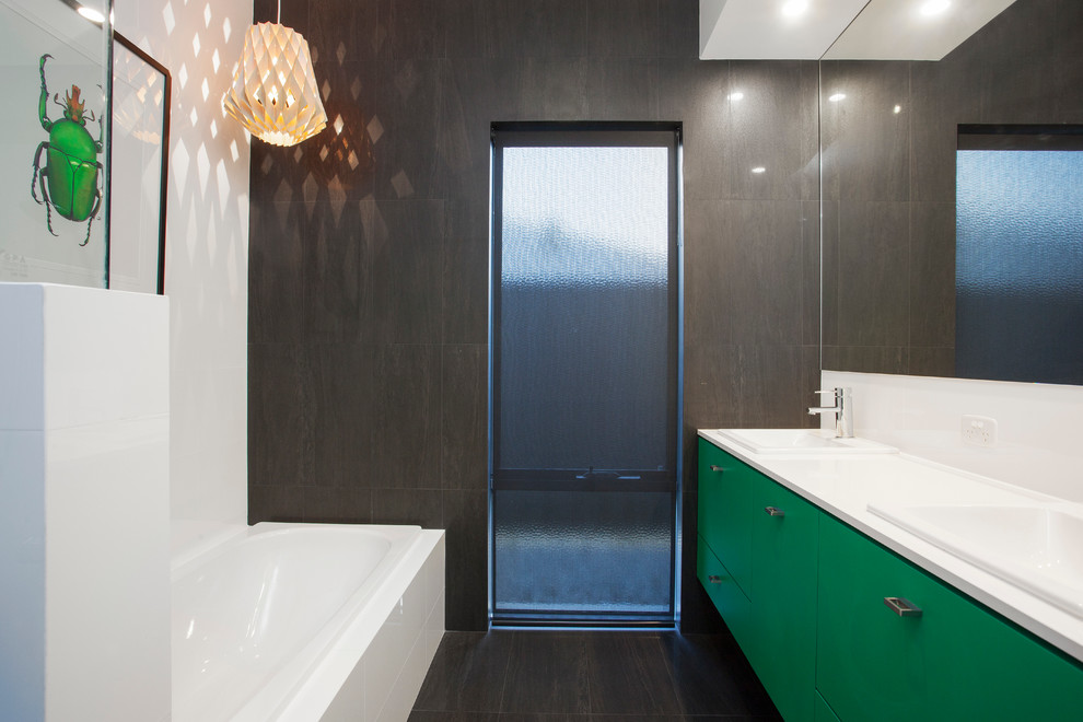 Cette photo montre une salle de bain moderne pour enfant avec des portes de placards vertess, un plan de toilette en quartz modifié, une baignoire posée, un carrelage noir, des carreaux de porcelaine, un mur blanc et un sol en carrelage de porcelaine.