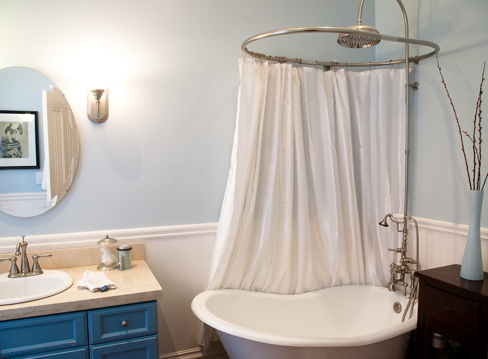 Exemple d'une petite salle de bain chic avec une baignoire sur pieds, des portes de placard bleues, un placard avec porte à panneau encastré, un mur bleu, un lavabo encastré et un plan de toilette noir.