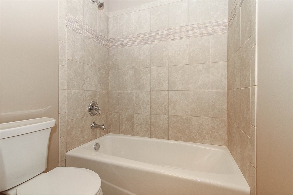 Bild på ett mellanstort vintage en-suite badrum, med ett integrerad handfat, luckor med upphöjd panel, skåp i mörkt trä, granitbänkskiva, en dusch/badkar-kombination, beige kakel, keramikplattor, beige väggar och klinkergolv i keramik