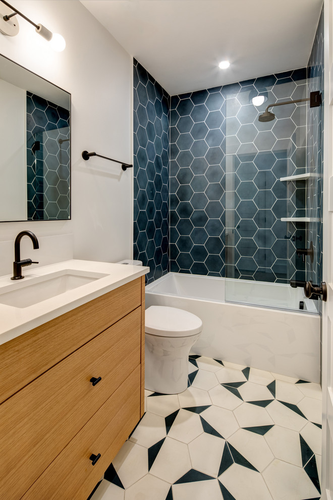 Пример оригинального дизайна: ванная комната в современном стиле с фасадами цвета дерева среднего тона, ванной в нише, душем над ванной, серой плиткой, белыми стенами, душевой кабиной, врезной раковиной, разноцветным полом и белой столешницей