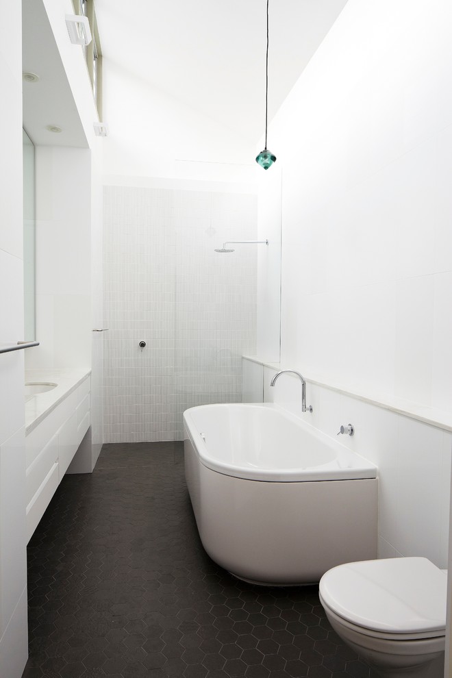 Idéer för ett mellanstort modernt en-suite badrum, med ett undermonterad handfat, släta luckor, vita skåp, marmorbänkskiva, ett platsbyggt badkar, en dusch i en alkov, en vägghängd toalettstol, grå kakel, keramikplattor, vita väggar och klinkergolv i keramik