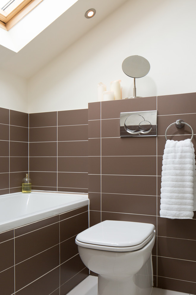 Design ideas for a small contemporary ensuite bathroom in Other with a built-in bath, a one-piece toilet, brown tiles, ceramic tiles, beige walls, ceramic flooring and solid surface worktops.
