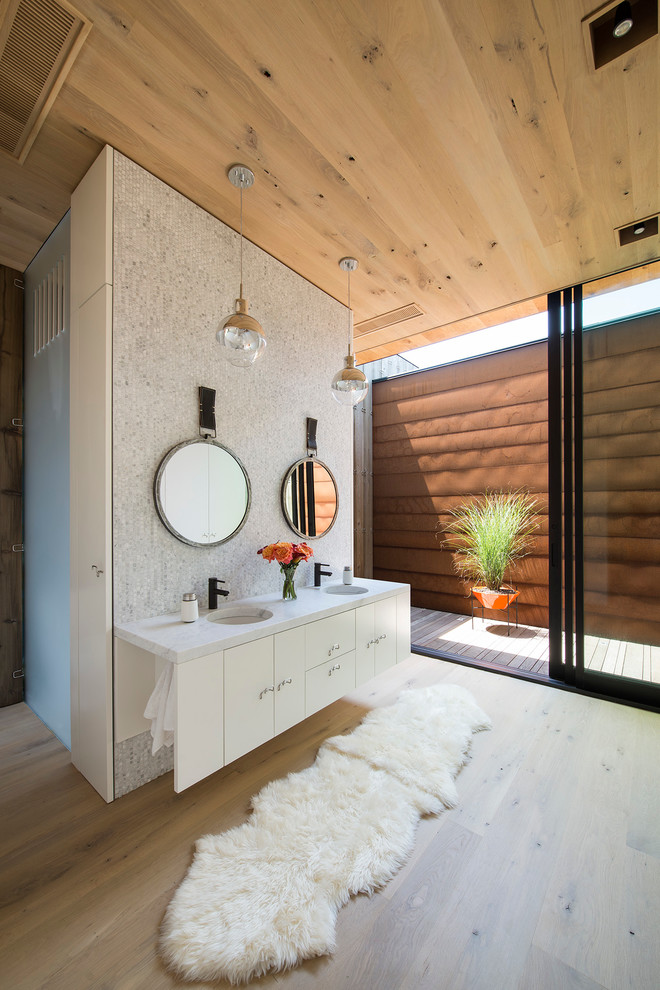 Exemple d'une salle de bain principale tendance de taille moyenne avec des portes de placard blanches, une douche ouverte, un placard à porte plane, un carrelage blanc, mosaïque, un sol en bois brun et un lavabo encastré.