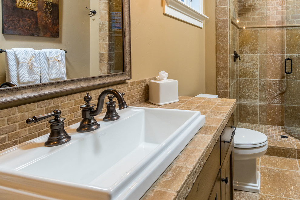 Exempel på ett stort medelhavsstil en-suite badrum, med luckor med upphöjd panel, beige skåp, brun kakel, kakelplattor, beige väggar, kalkstensgolv, ett nedsänkt handfat och brunt golv
