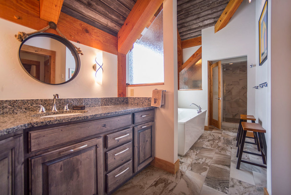 Modelo de cuarto de baño principal rural grande con armarios con paneles con relieve, puertas de armario de madera en tonos medios, paredes grises, lavabo bajoencimera y encimera de granito