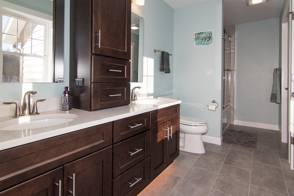 Mid-sized transitional master gray tile and porcelain tile porcelain tile bathroom photo in Milwaukee with recessed-panel cabinets, dark wood cabinets, a two-piece toilet, blue walls, an undermount sink and quartzite countertops