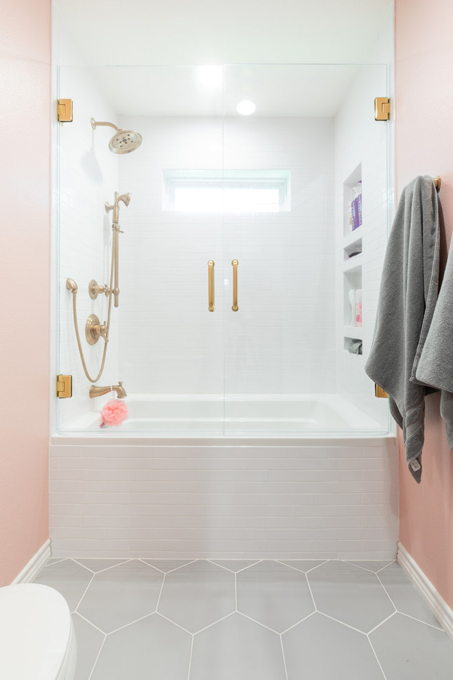 Cette photo montre une salle de bain chic de taille moyenne pour enfant avec un placard à porte shaker, des portes de placard blanches, une baignoire posée, un combiné douche/baignoire, WC séparés, un carrelage blanc, un carrelage métro, un mur rose, un sol en carrelage de porcelaine, un lavabo encastré, un plan de toilette en quartz modifié, un sol gris, une cabine de douche à porte battante, un plan de toilette blanc, meuble simple vasque, meuble-lavabo encastré et du papier peint.