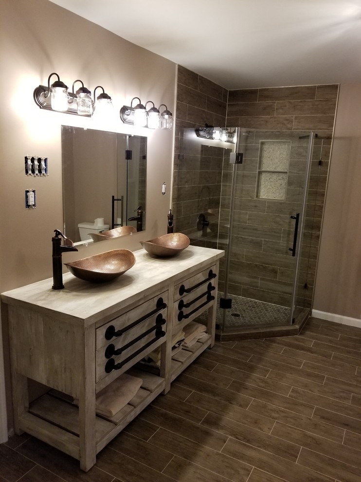 Exempel på ett mellanstort rustikt grå grått badrum med dusch, med skåp i slitet trä, en hörndusch, brun kakel, porslinskakel, beige väggar, klinkergolv i porslin, ett fristående handfat, träbänkskiva, brunt golv och dusch med gångjärnsdörr