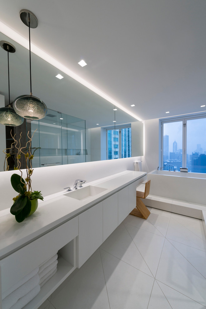 Modernes Badezimmer mit integriertem Waschbecken, flächenbündigen Schrankfronten, weißen Schränken, freistehender Badewanne, weißer Wandfarbe und weißer Waschtischplatte in Chicago