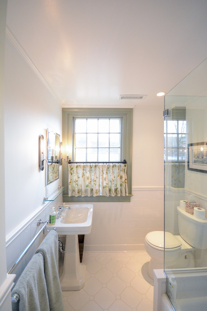 Photo of a medium sized rural family bathroom in New York with glass-front cabinets, white cabinets, a corner bath, a shower/bath combination, a one-piece toilet, white tiles, ceramic tiles, white walls, ceramic flooring, a pedestal sink and solid surface worktops.