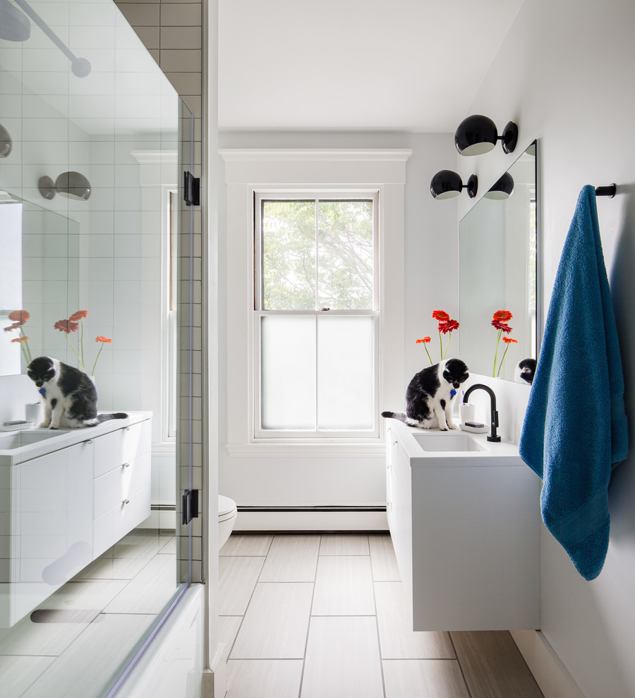 Inspiration for a medium sized modern family bathroom in Boston with flat-panel cabinets, white cabinets, an alcove bath, an alcove shower, a one-piece toilet, white tiles, metro tiles, grey walls, porcelain flooring, a submerged sink, solid surface worktops, beige floors and a hinged door.
