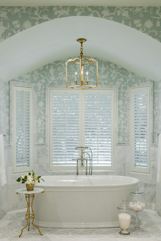 Cette photo montre une salle de bain chic avec une baignoire indépendante, un carrelage blanc, un mur bleu et un sol blanc.