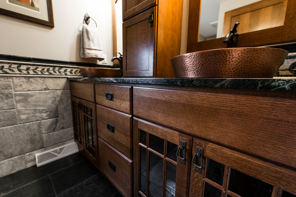 Cette image montre une grande salle d'eau traditionnelle en bois brun avec un placard à porte shaker, une baignoire en alcôve, un combiné douche/baignoire, WC séparés, un carrelage gris, du carrelage en ardoise, un mur beige, un sol en ardoise, une vasque et un plan de toilette en granite.