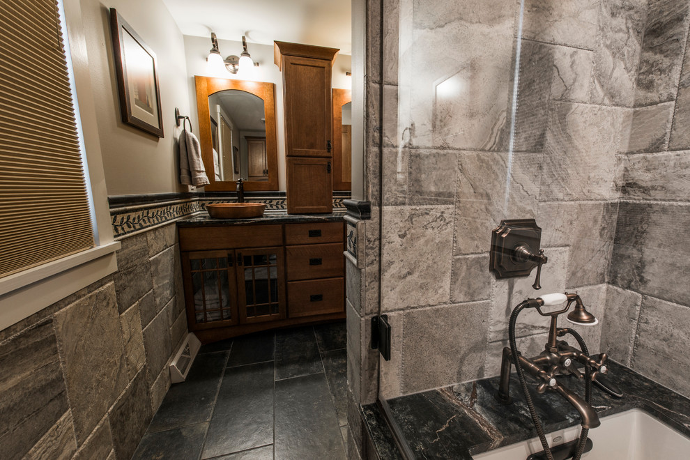 Cette image montre une grande salle d'eau traditionnelle en bois brun avec un placard à porte shaker, une baignoire en alcôve, un combiné douche/baignoire, WC séparés, un carrelage gris, du carrelage en ardoise, un mur beige, un sol en ardoise, une vasque et un plan de toilette en granite.