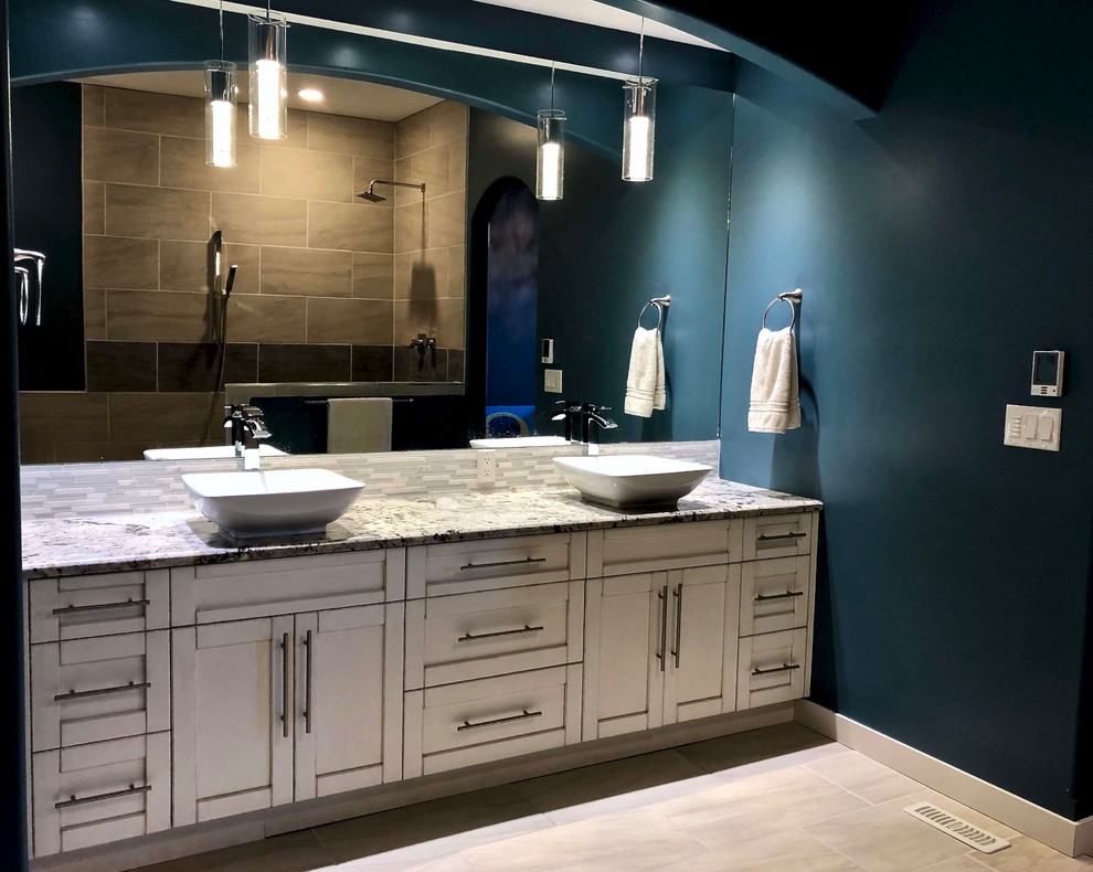 Пример оригинального дизайна: главная ванная комната в современном стиле с фасадами в стиле шейкер, светлыми деревянными фасадами, угловой ванной, открытым душем, разноцветной плиткой, стеклянной плиткой, синими стенами, полом из керамической плитки, настольной раковиной, столешницей из гранита, белым полом, открытым душем и разноцветной столешницей