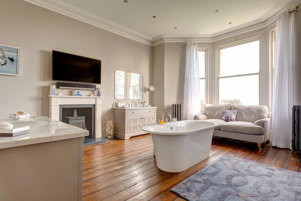 Immagine di una grande stanza da bagno classica con lavabo integrato, consolle stile comò, ante beige, top in granito, vasca freestanding, pareti beige e pavimento in legno massello medio