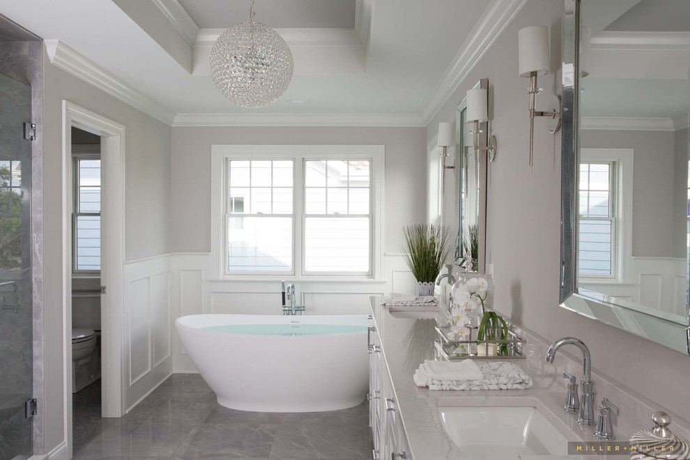 Exempel på ett stort lantligt vit vitt en-suite badrum, med skåp i shakerstil, vita skåp, ett fristående badkar, en dusch i en alkov, grå väggar, ett nedsänkt handfat, bänkskiva i akrylsten och grått golv