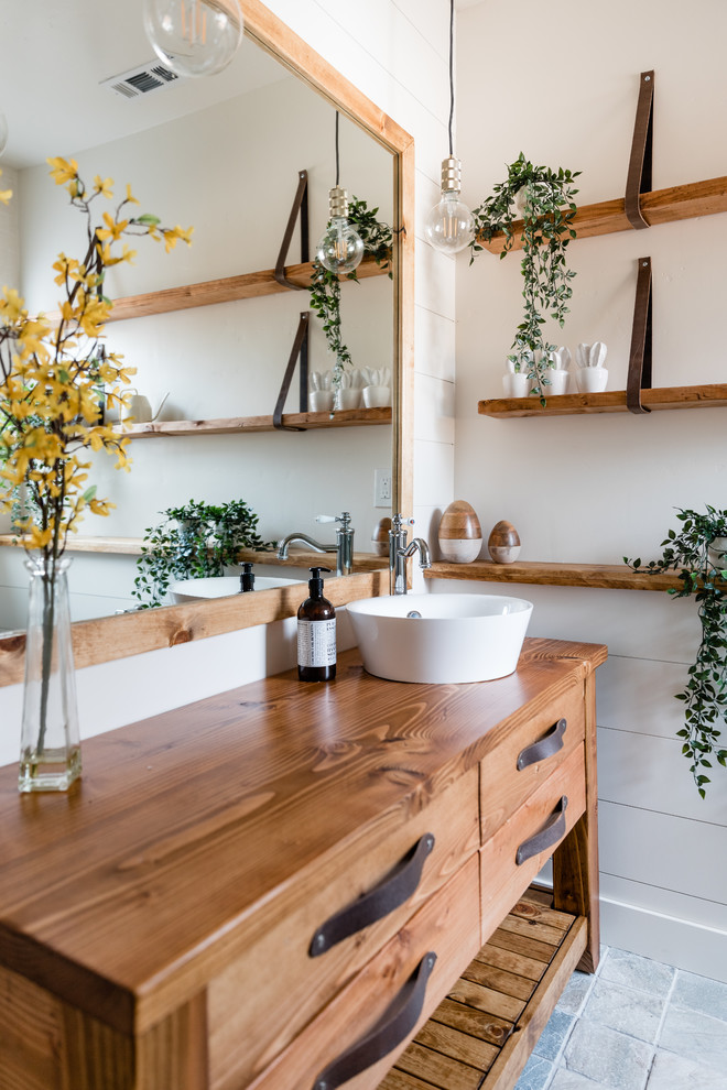 Inspiration for a country gray floor bathroom remodel in Sacramento with furniture-like cabinets, medium tone wood cabinets, white walls, a vessel sink, wood countertops and brown countertops