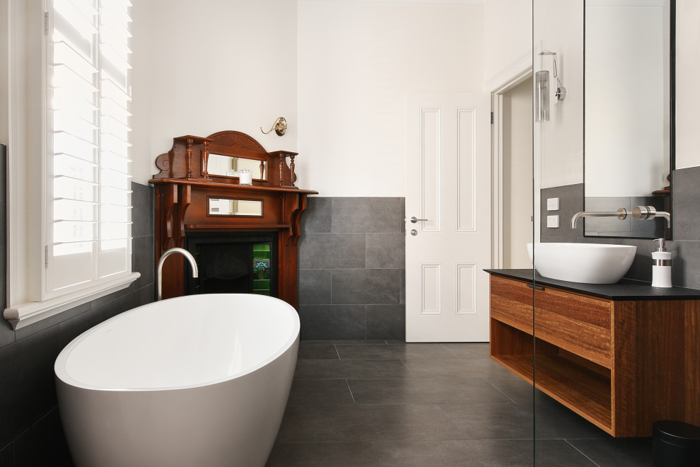 Inspiration för ett funkis svart svart en-suite badrum, med skåp i mörkt trä, ett fristående badkar, grå kakel, vita väggar, ett fristående handfat och grått golv