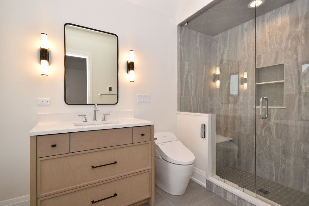 Example of a transitional 3/4 gray tile and white tile gray floor and single-sink bathroom design in Chicago with recessed-panel cabinets, medium tone wood cabinets, a two-piece toilet, white walls, an undermount sink, quartz countertops, a hinged shower door, white countertops and a built-in vanity