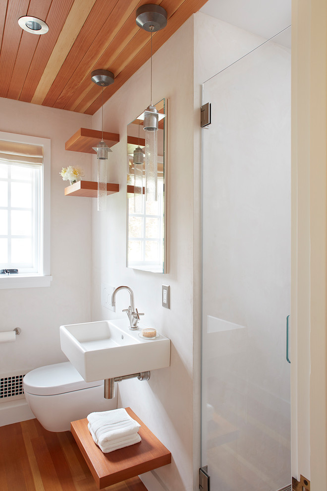 Réalisation d'une petite salle de bain design avec WC suspendus, un mur blanc, un sol en bois brun, un lavabo suspendu, un sol marron et une cabine de douche à porte battante.