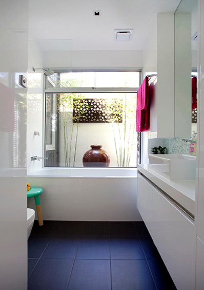 Photo of a small contemporary bathroom in Melbourne with a built-in sink, flat-panel cabinets, white cabinets, an alcove bath, a shower/bath combination and white walls.