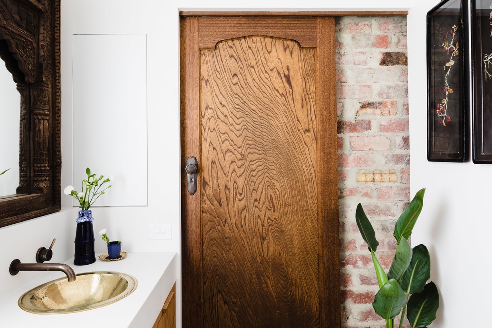 Ejemplo de cuarto de baño mediterráneo con armarios con paneles lisos, puertas de armario de madera oscura, paredes blancas, lavabo encastrado y encimeras blancas