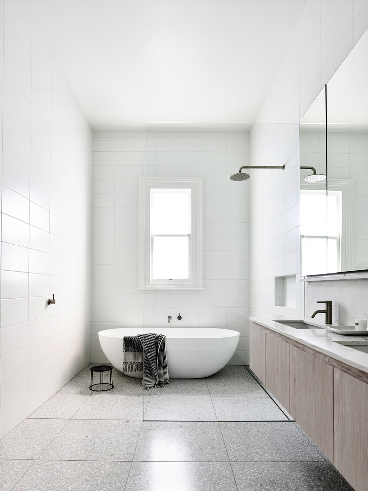 Источник вдохновения для домашнего уюта: главная ванная комната в стиле модернизм с плоскими фасадами, светлыми деревянными фасадами, отдельно стоящей ванной, белой плиткой, врезной раковиной, серым полом и белой столешницей