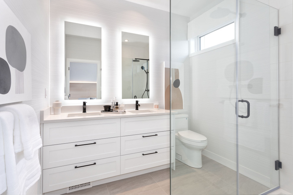 Mid-sized danish master white tile and ceramic tile porcelain tile, beige floor, double-sink and wallpaper bathroom photo in Vancouver with shaker cabinets, white cabinets, a one-piece toilet, white walls, an undermount sink, quartzite countertops, a hinged shower door, white countertops and a built-in vanity