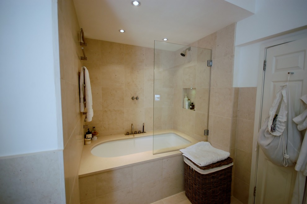 Design ideas for a medium sized contemporary ensuite bathroom in London with a console sink, flat-panel cabinets, dark wood cabinets, solid surface worktops, a claw-foot bath, a shower/bath combination, a wall mounted toilet, beige tiles, stone slabs, white walls and limestone flooring.