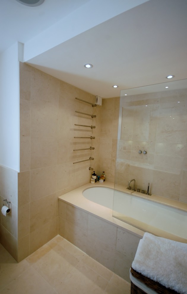 Inspiration for a medium sized contemporary ensuite bathroom in London with a console sink, flat-panel cabinets, dark wood cabinets, solid surface worktops, a claw-foot bath, a shower/bath combination, a wall mounted toilet, beige tiles, stone slabs, white walls and limestone flooring.